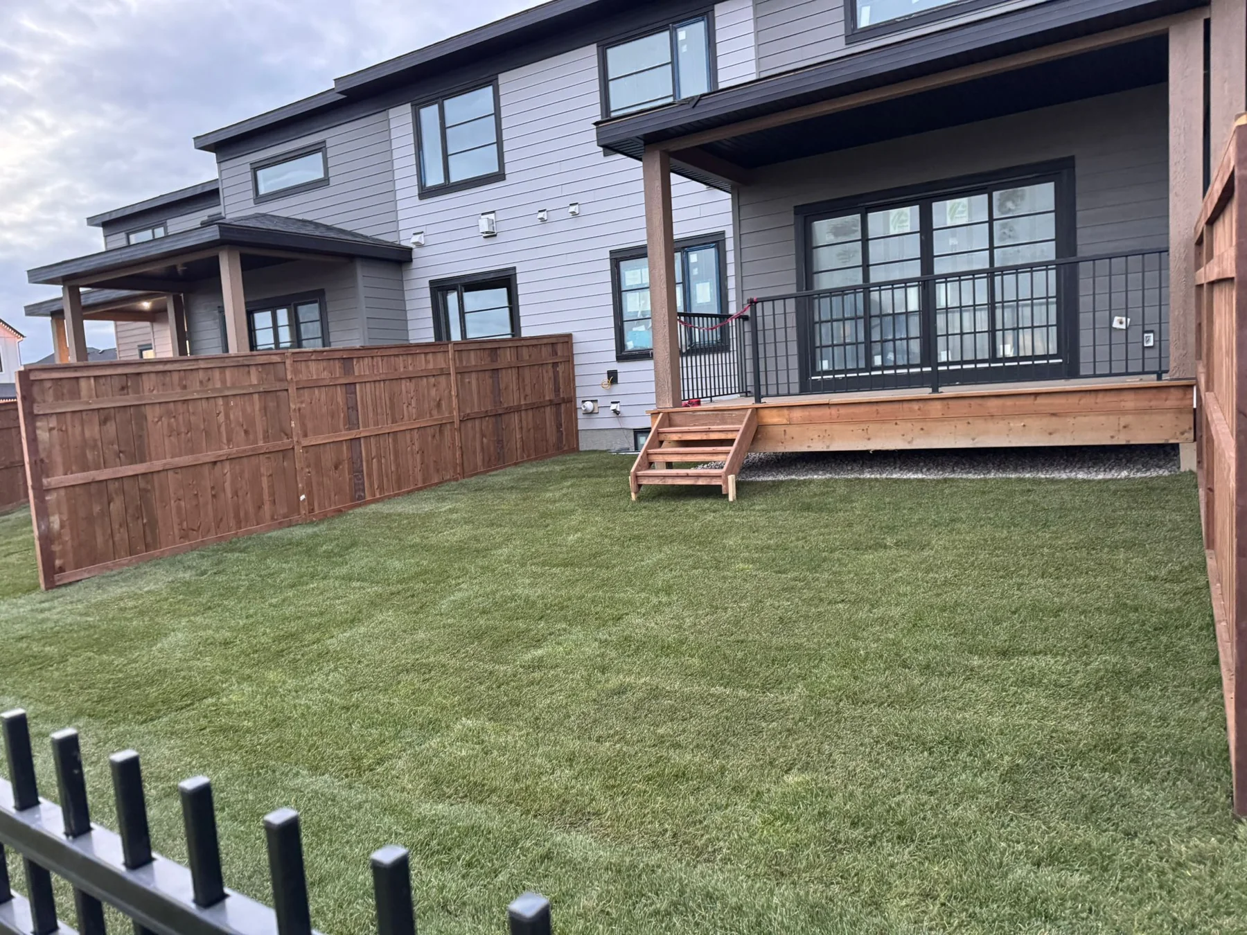 Completed fenced backyard with fresh sod and a finished raised deck